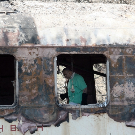 Съдебен лекар прави пореден вътрешния оглед на изгорелите вагони в търсене на улики от овъглените трупове