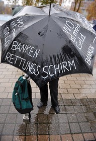 Жертва на фалита на ”Леман” протестира във Франкфурт под чадър с надпис ”Къде са ми парите”