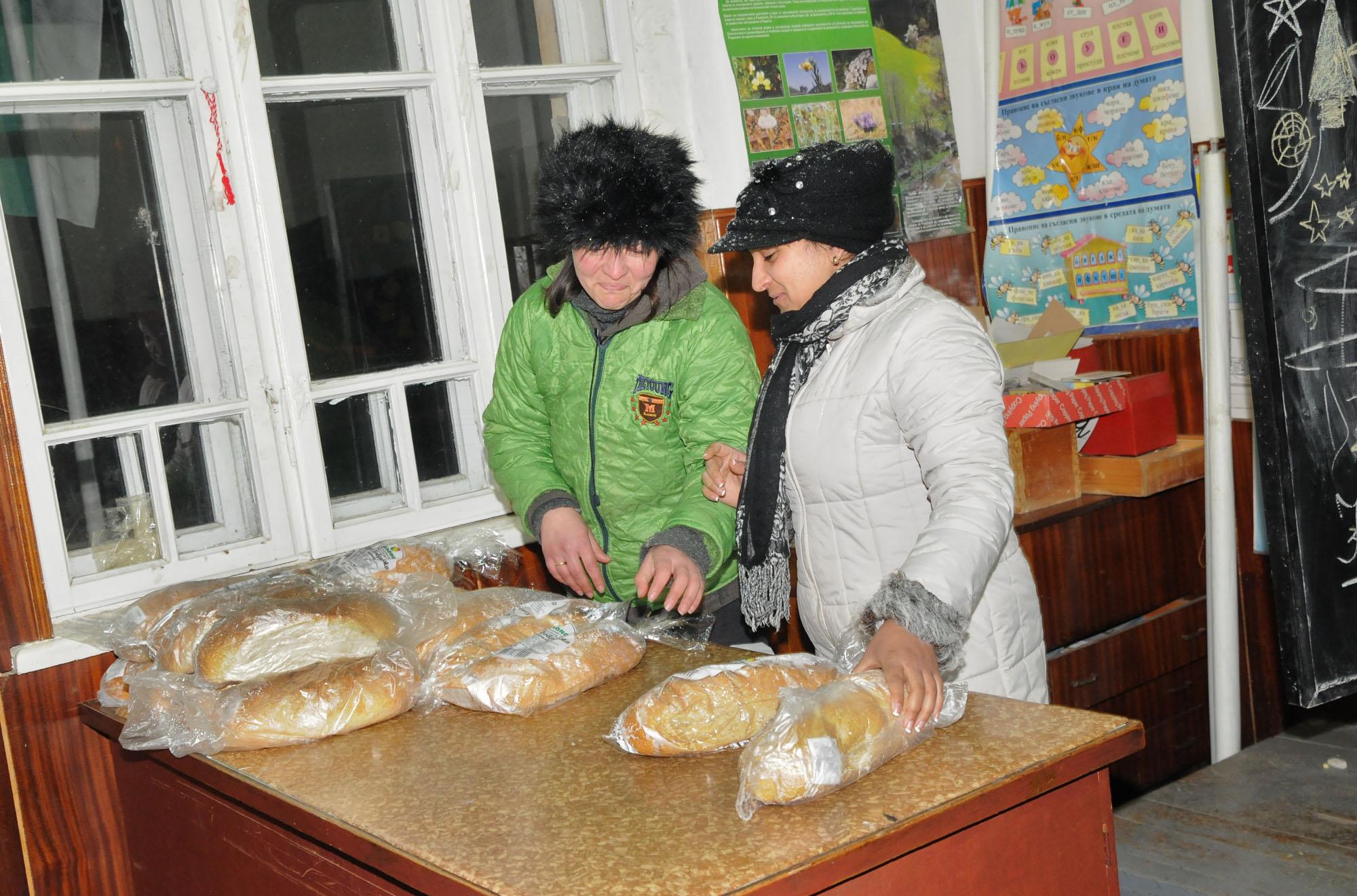 Kметът на село Бисер Златка Вълкова (вляво) разпределя пристигналия хляб за местните хора