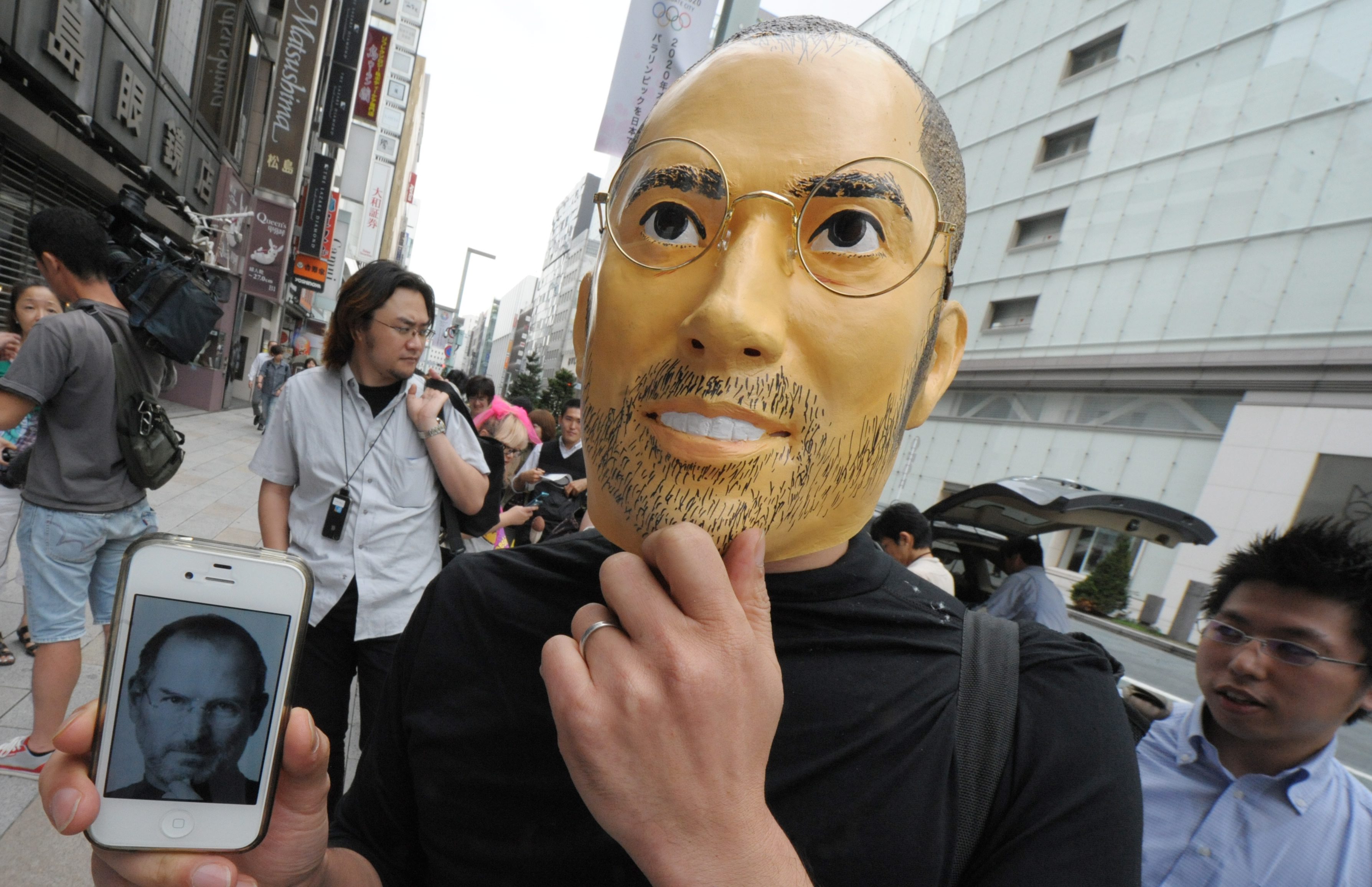 Фен на Apple с маска на Стив Джобс на опашка за iPhone 5 в Япония