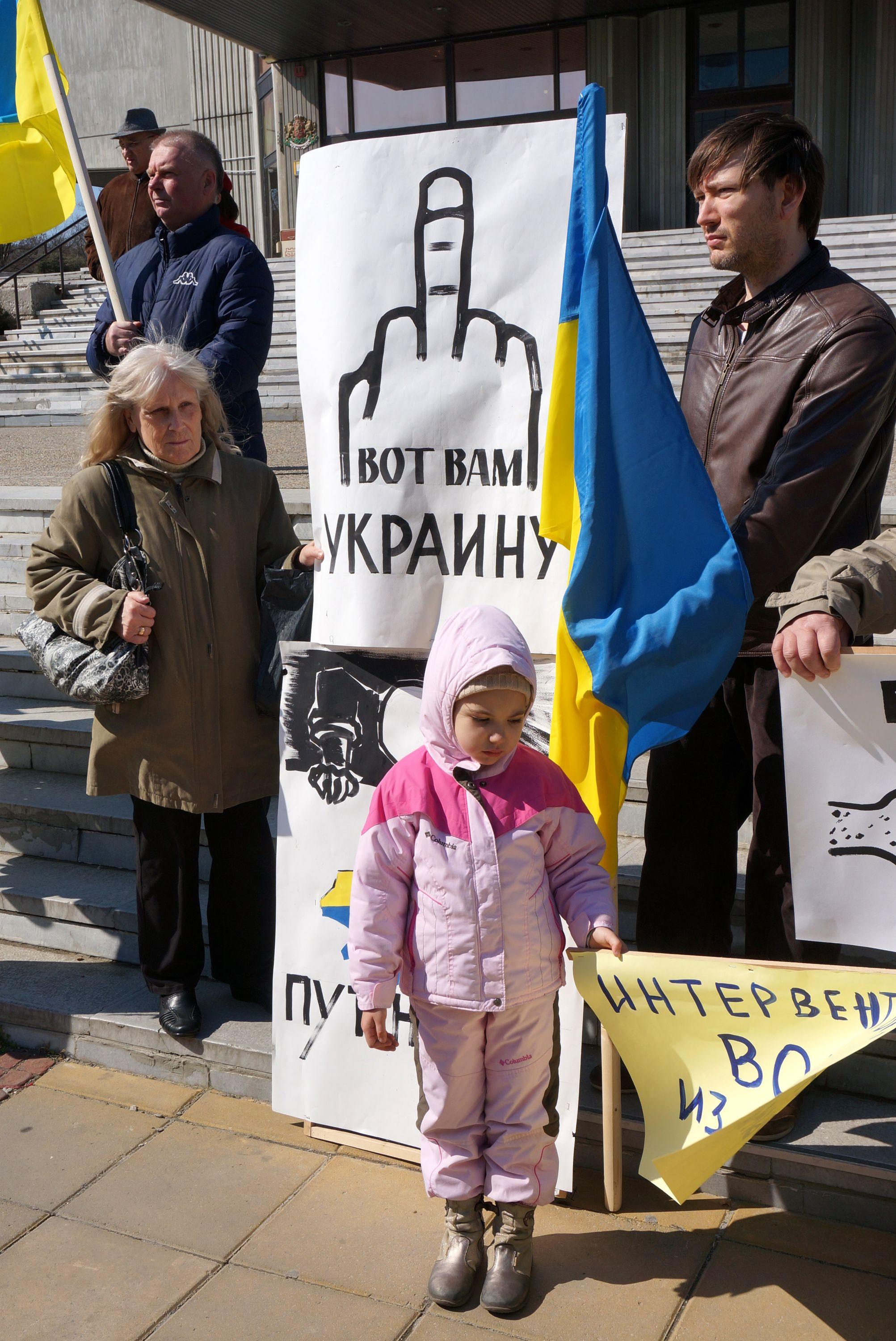 Протестиращи, издигнали плакати, сред тях и малко дете