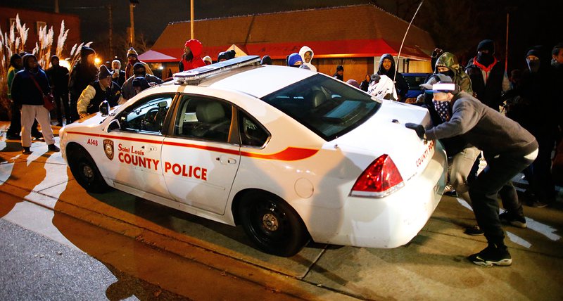 Протестиращи обръщат полицейска кола при протест във Фъргюсън след решението на съдебното жури да не бъде съден полицая, застрел