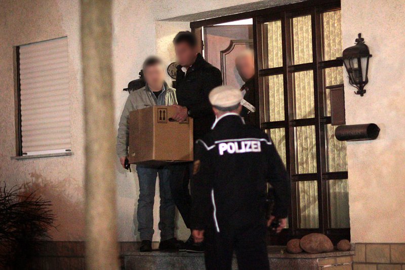 Полицейски служител изнася кутия с вещи от дома на Андреас Лубиц в Монтабауер, северно от Франкфурт