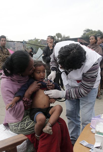 Лекар преглажда малко дете сред развалините в Непал