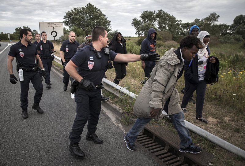 Френски полицаи ескортират мигранти от Еритрея на пътя, недалеч от Кале и тунела под Ламанша