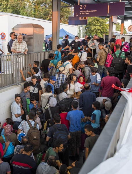 Бежанците, дошли с влак от Унгария, стоят на стълбище зад кордона на германските федерални полиция на гарата в Розенхайм