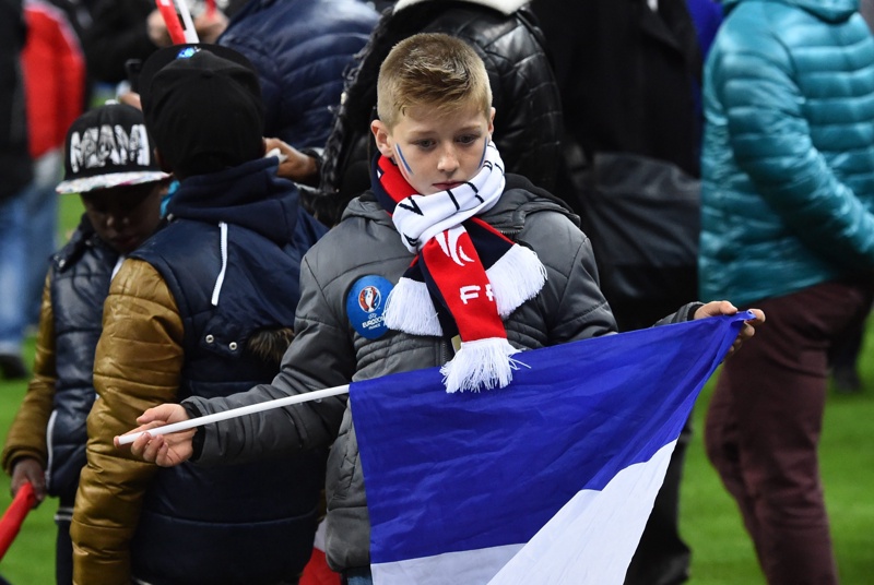 Дете държи свалено знамето на Франция на стадиона след взривовете в района по време на приятелски мач