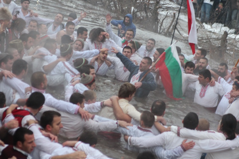 Мъже, пременени в народни носии, играят хоро в реката