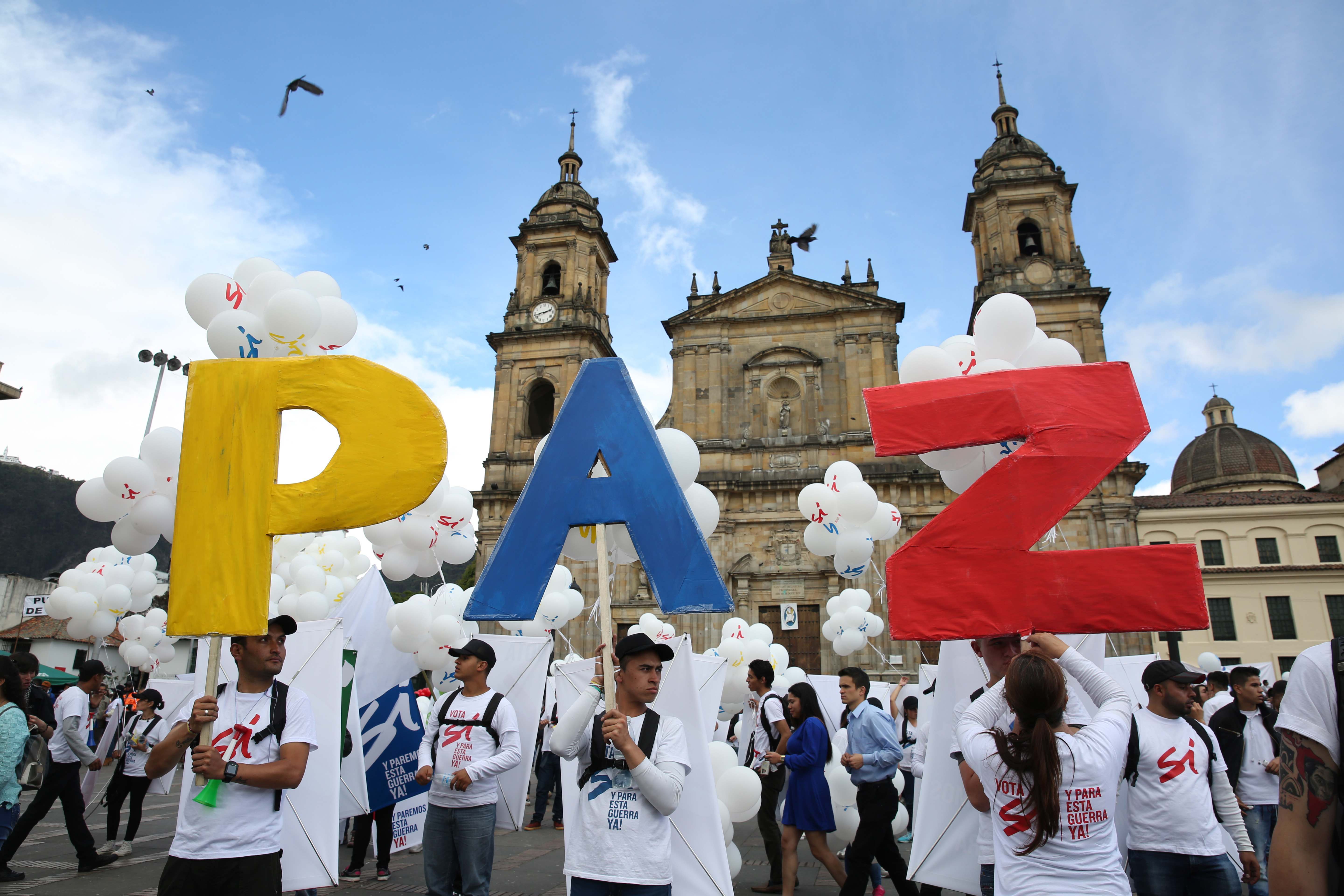 Демонстранти в Богота държат плакат с надпис ”Мир”, докато се подписва мирното споразумение