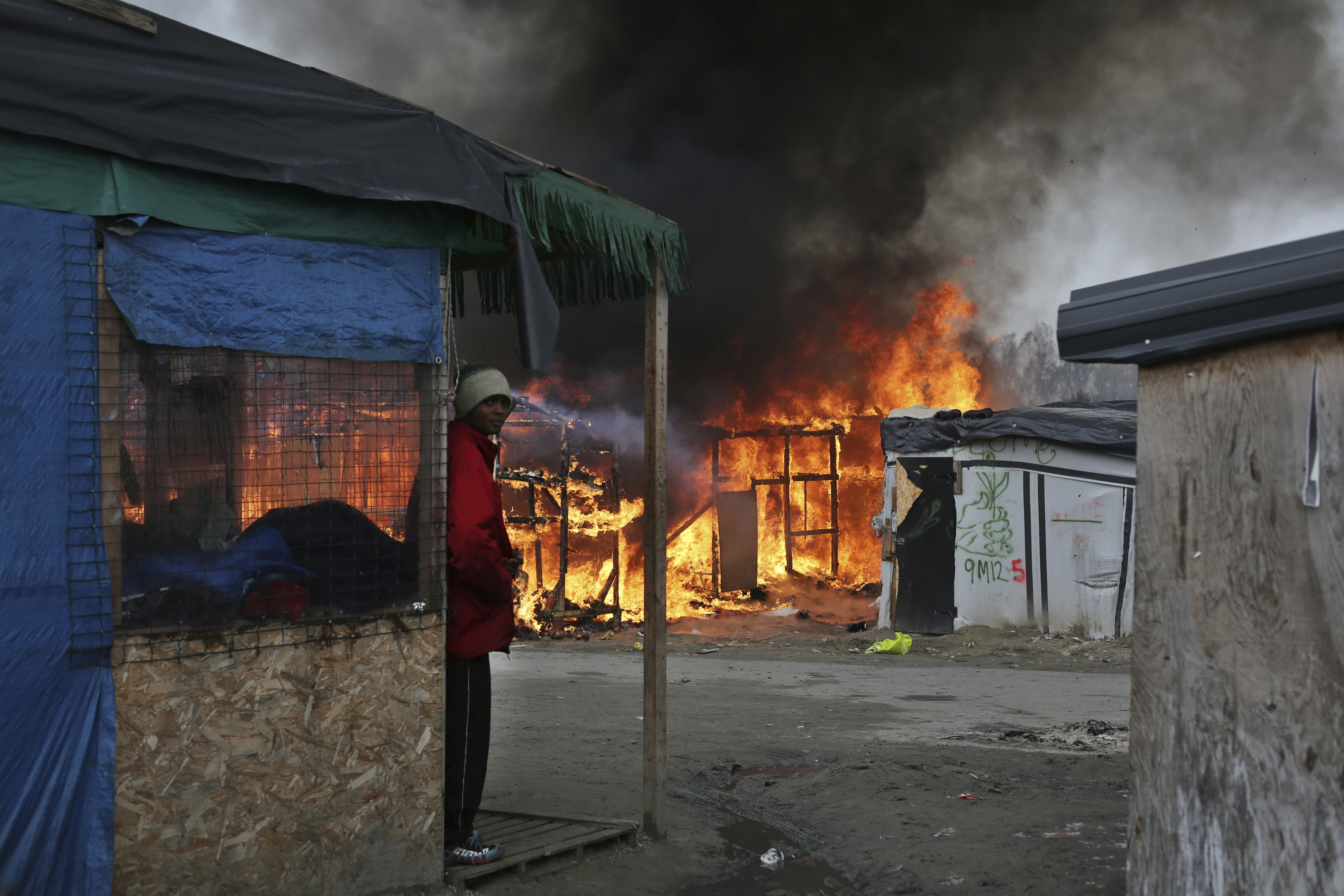 Мигрант сред горящия лагер ”Джунглата” край Кале