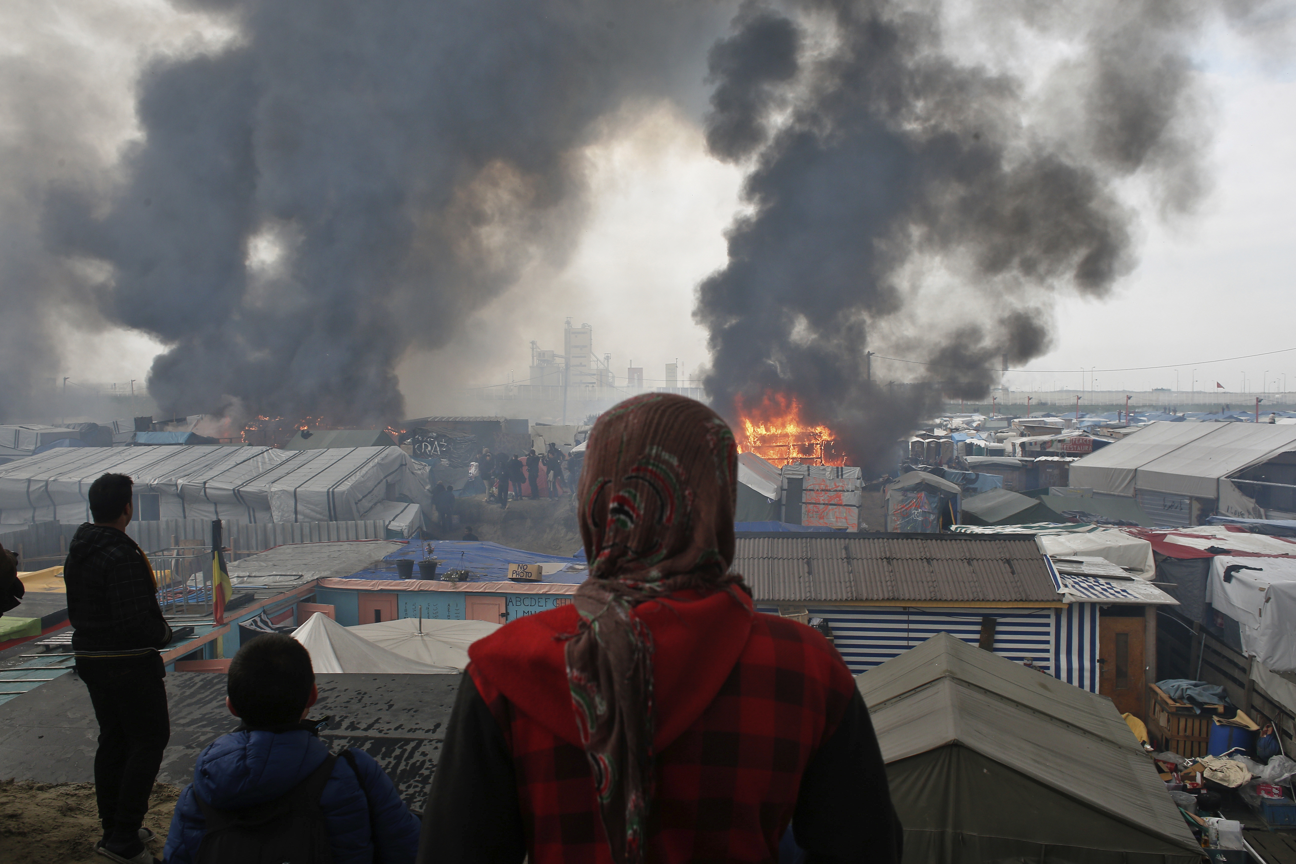 Мигранти наблюдават подпаления лагер ”Джунглата” край Кале