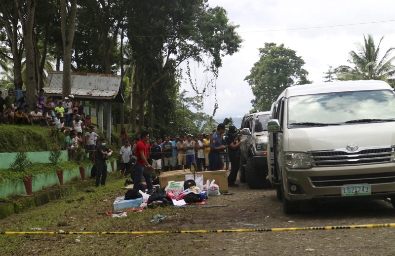 Любопитни селяни във Филипините гледат полицейските действия след операцията в Макилала