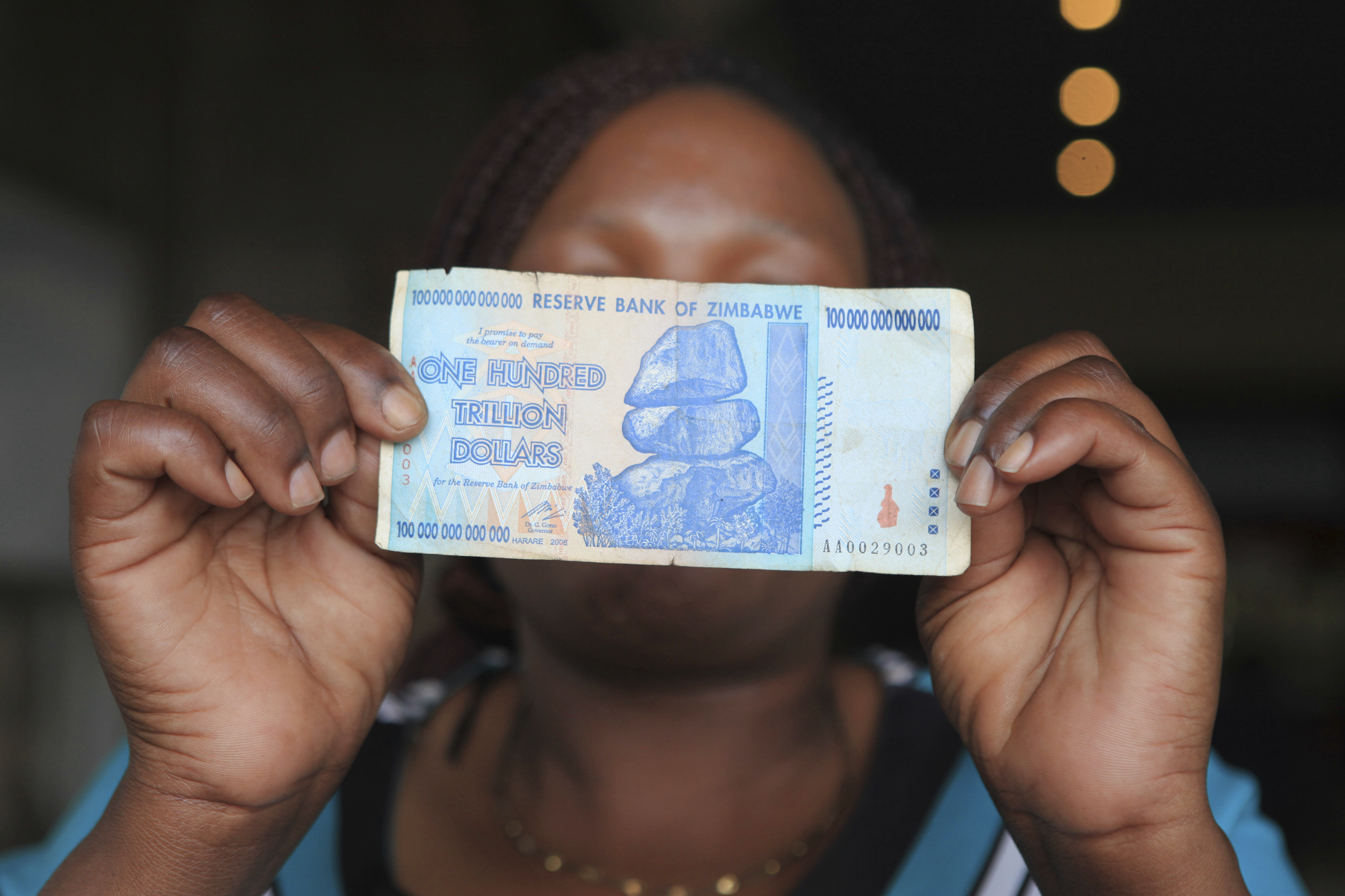 Жена в Хараре показва банкнота от 100 трилиона долара