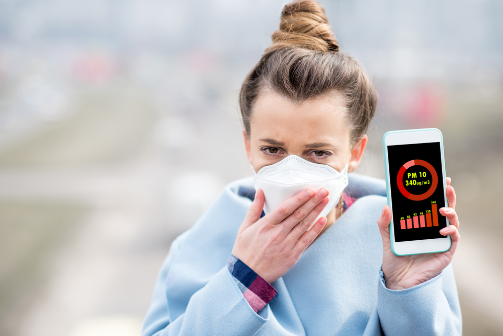 Жена показва на телефона си колко е замърсен въздухът
