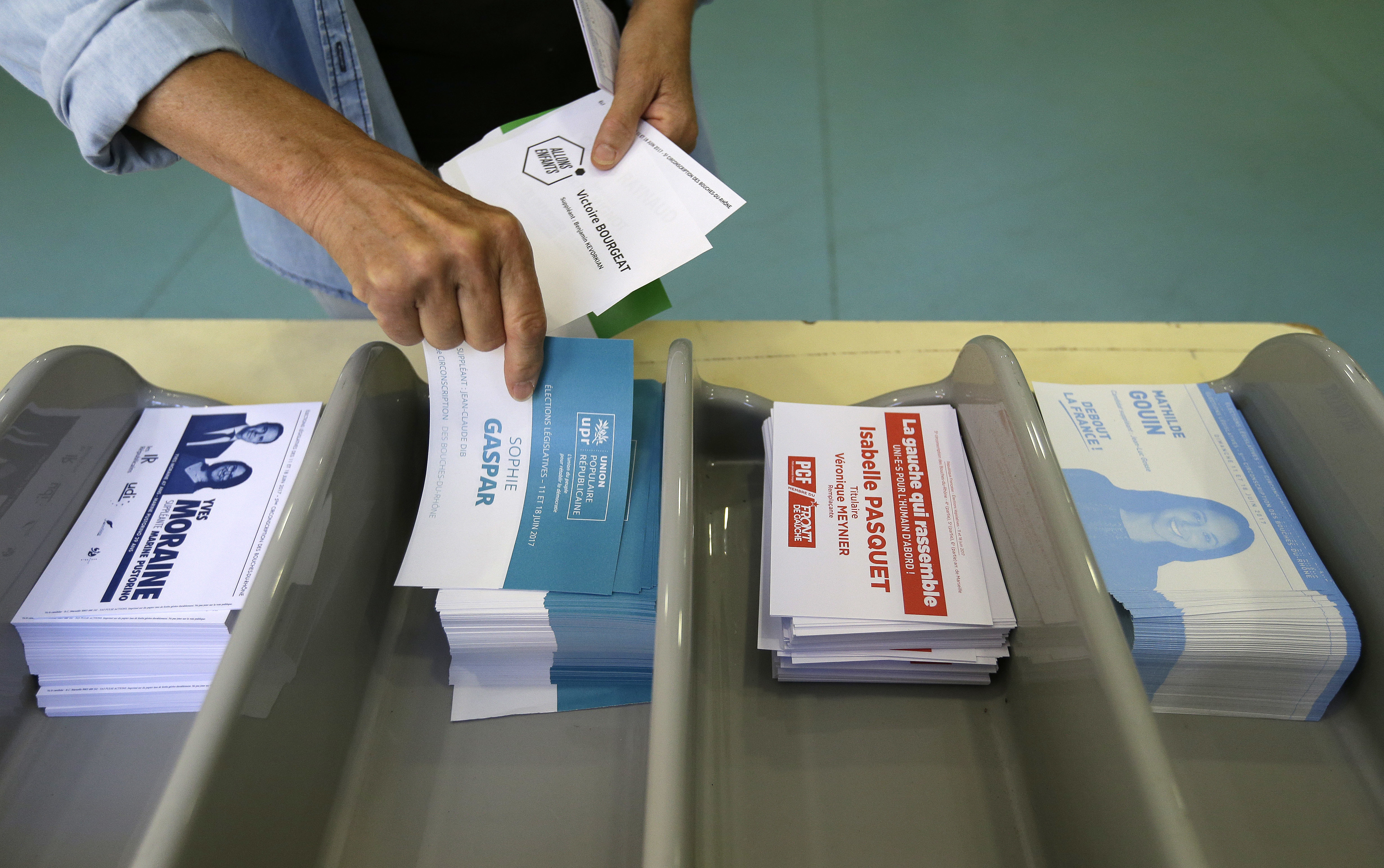 Избирател взема бюлетини преди да гласува на парламентарните избори във Франция