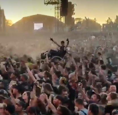 Момче в инвалидна количка се носи на ръцете на тълпата (краудсърфинг) на рок концерт