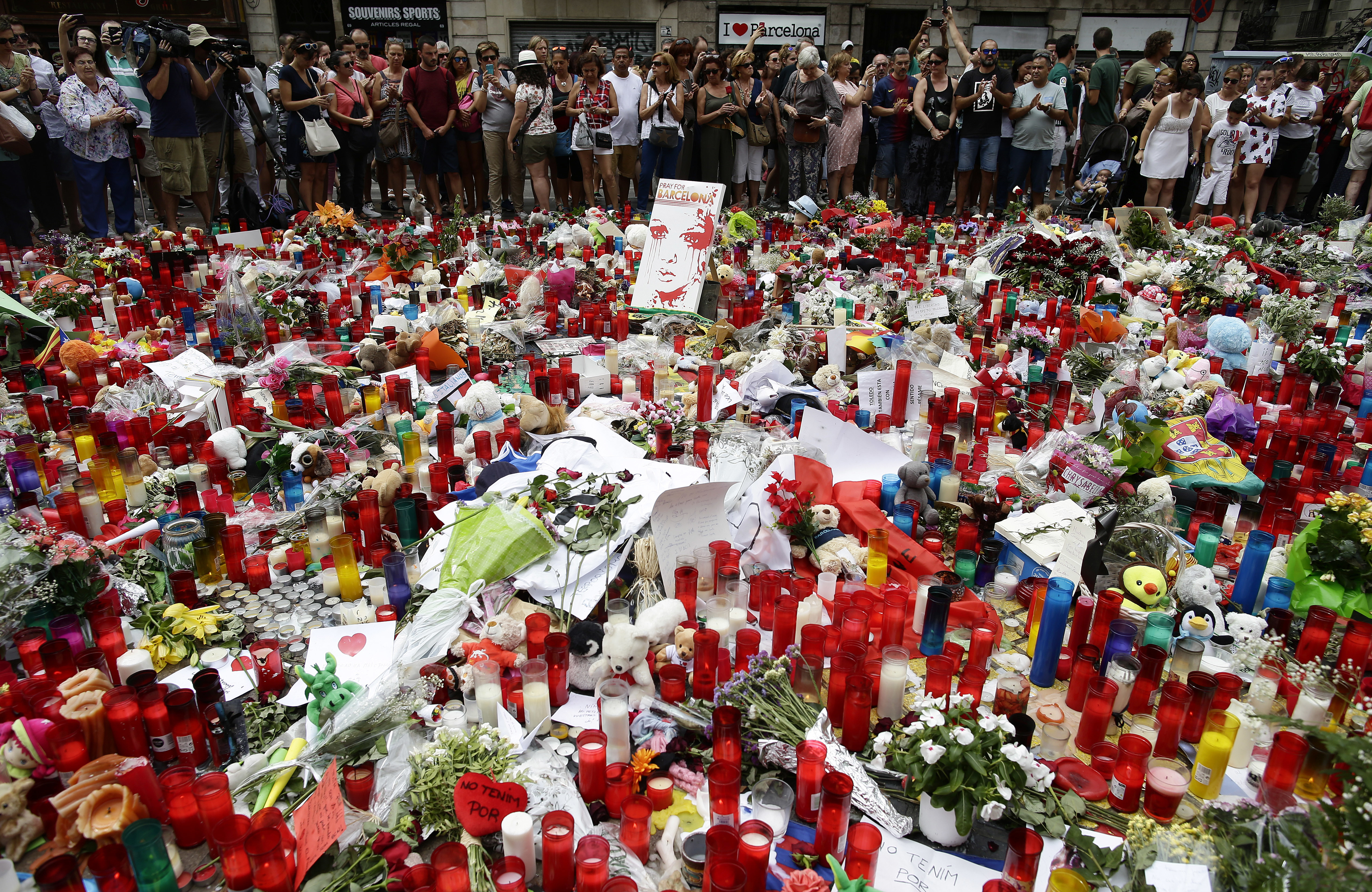 Хора се тълпят около отрупаното с цветя и свещи място на трагедията в Барселона