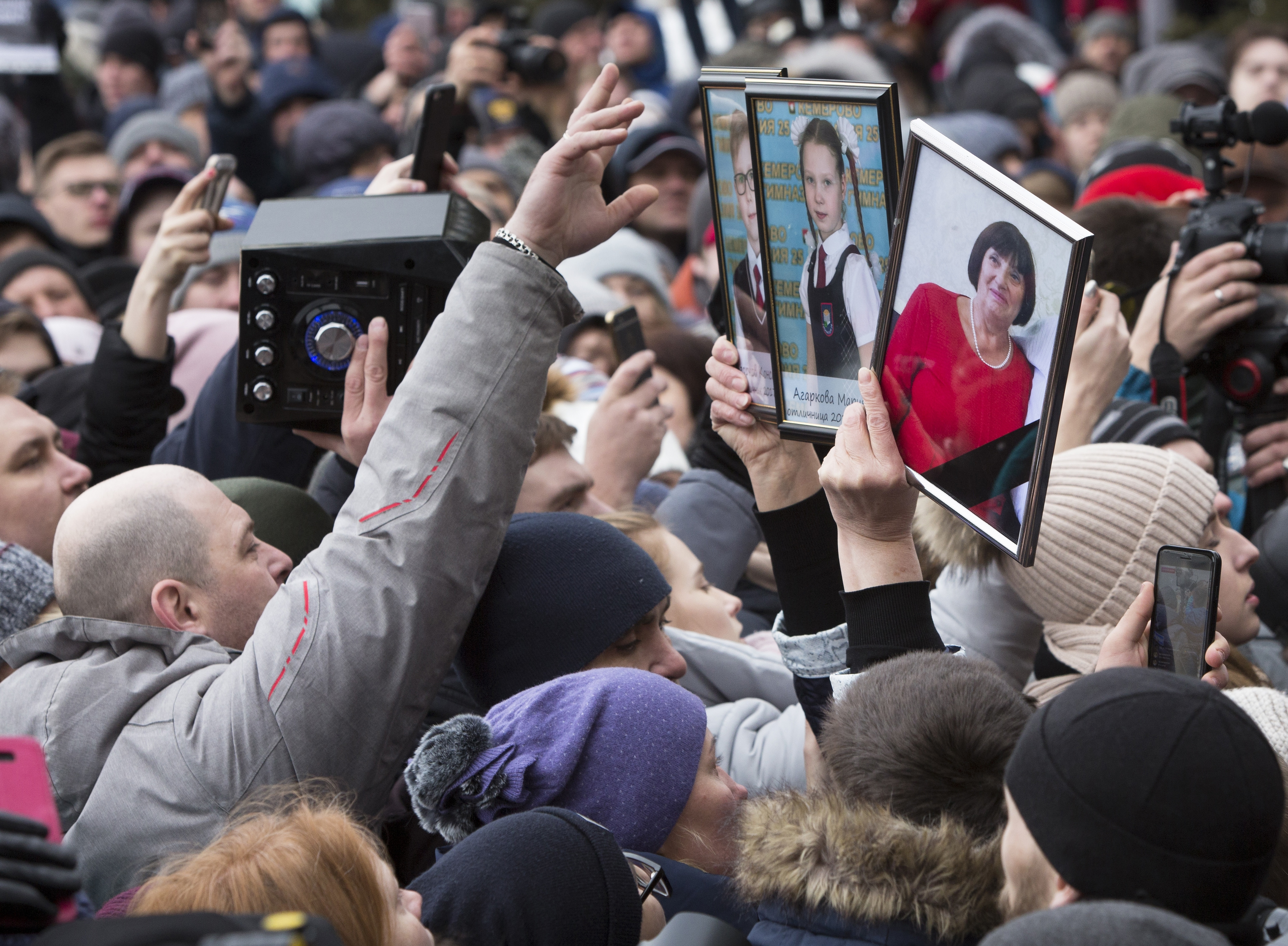 Протестиращи държат снимки на загинали близки при пожара в мола в Кемерово