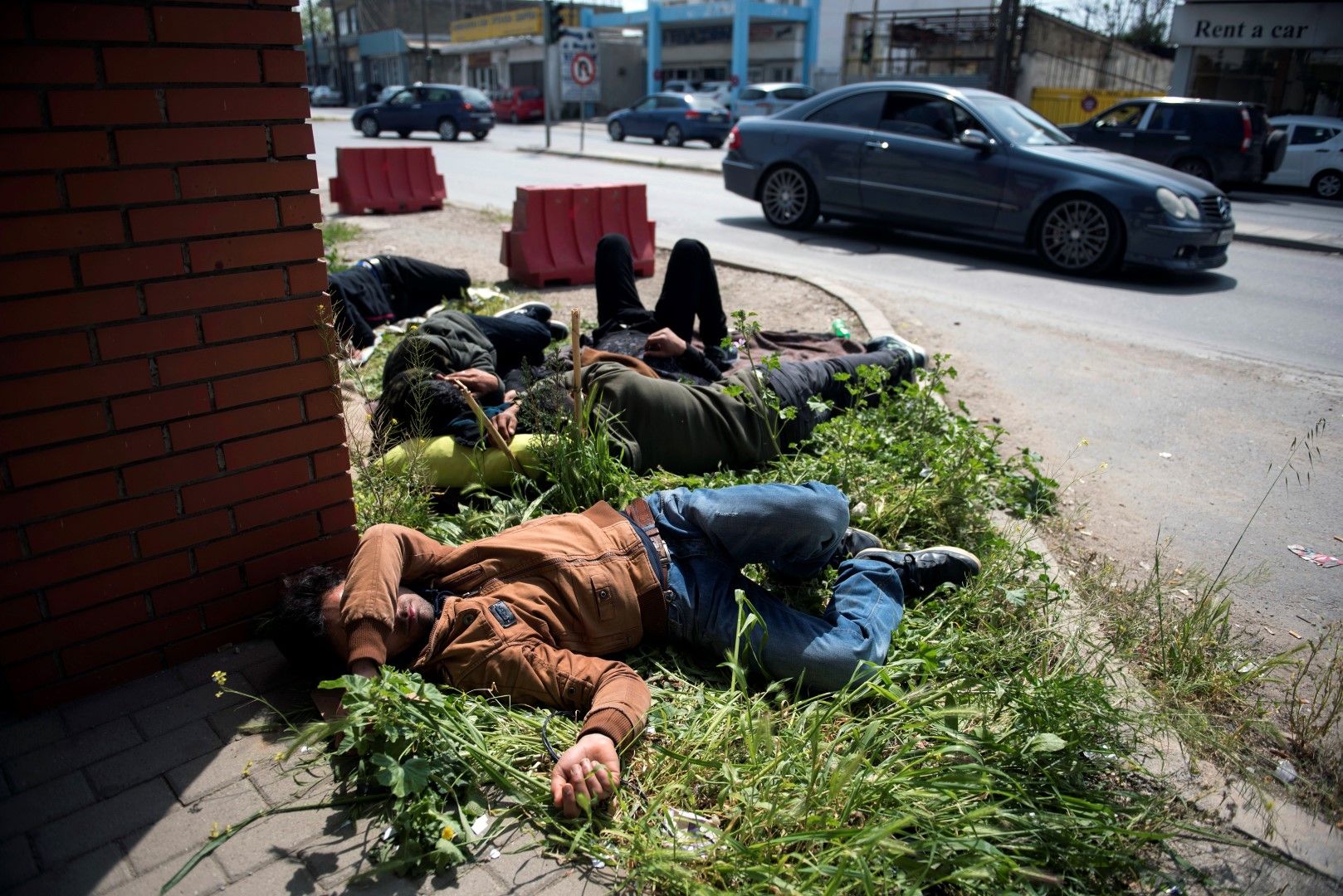 Мигранти спят на тревата край полицейски участък в Солун