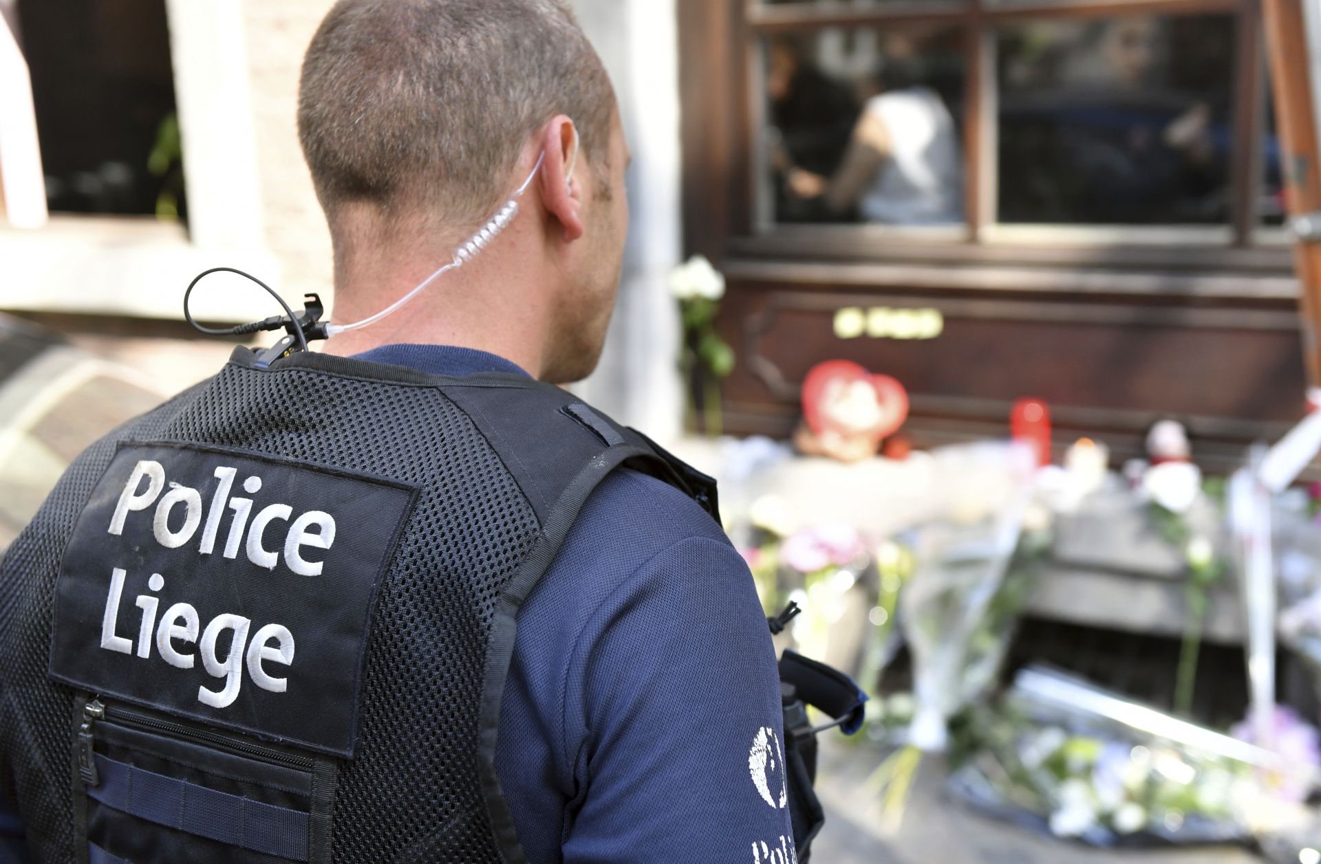 Полицай  гледа мемориала от цветя на мястото на стрелбата