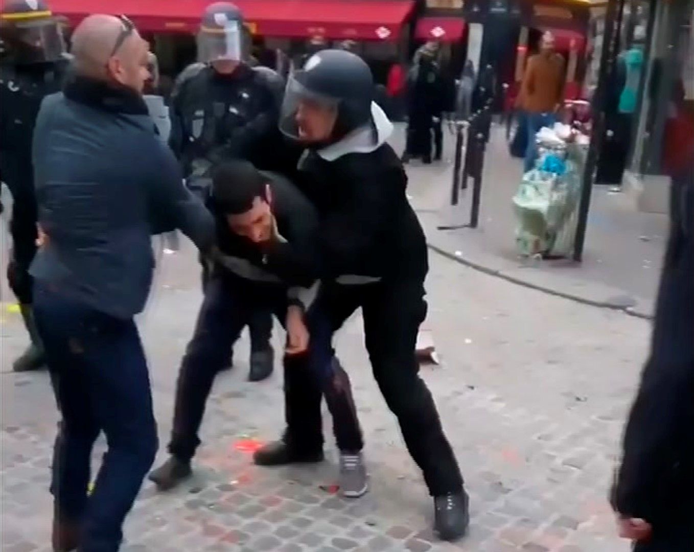 Бенала (вдясно) с полицейска каска бие протестиращ