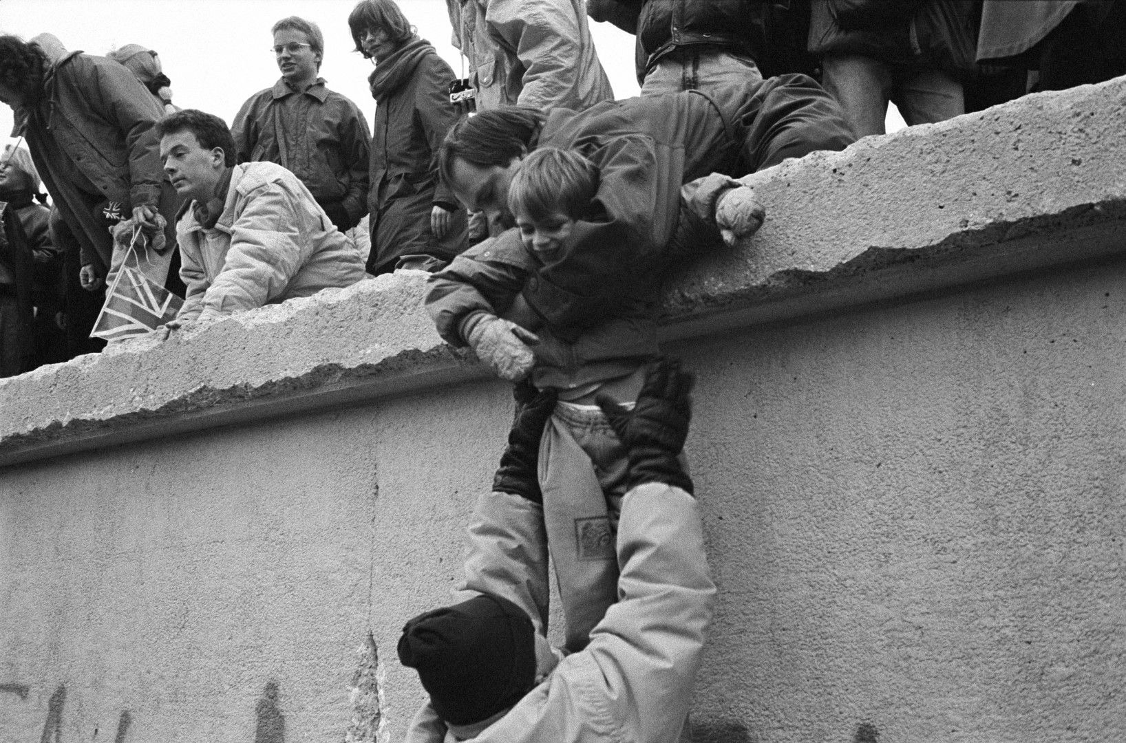  След като стената пада символично, стотици жители на ГДР се катерят по нея 
