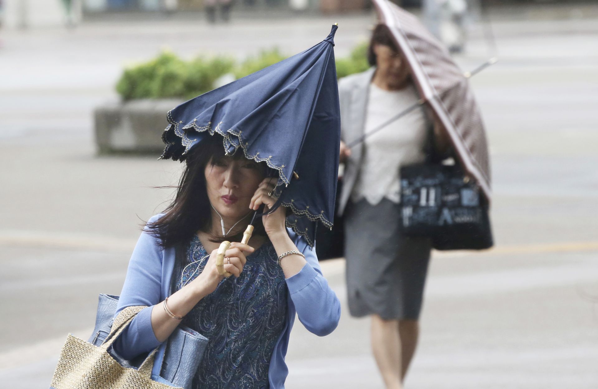 Пешеходците се опитват да държат чадърите, докато се борят със силни ветрове в Йокохама, близо до Токио