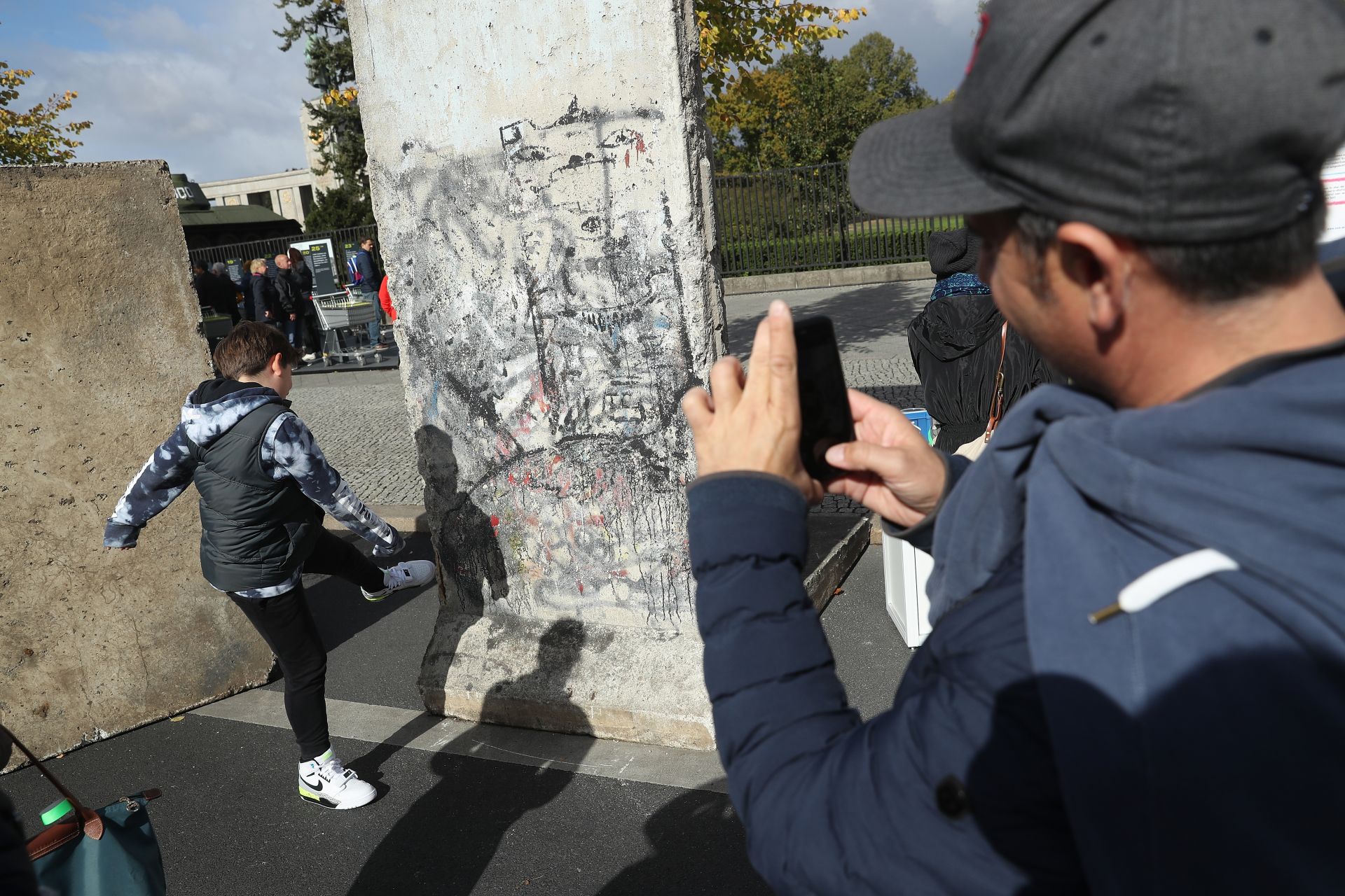 Баща фотографира сина си, който се преструва, че бута Берлинската стена по време на тържествата, отбелязващи деня на немското единство на 3 октомври 2018 г. в Берлин