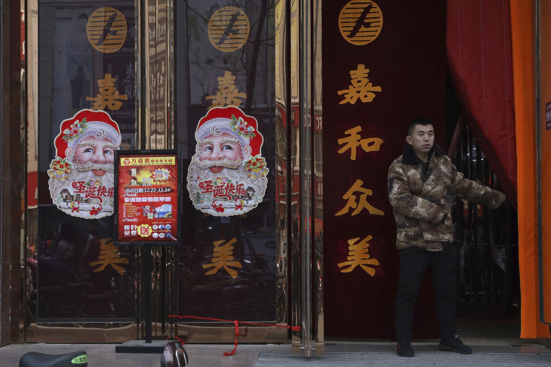 Работник пази входа на магазин, украсен с Дядо Коледа 
