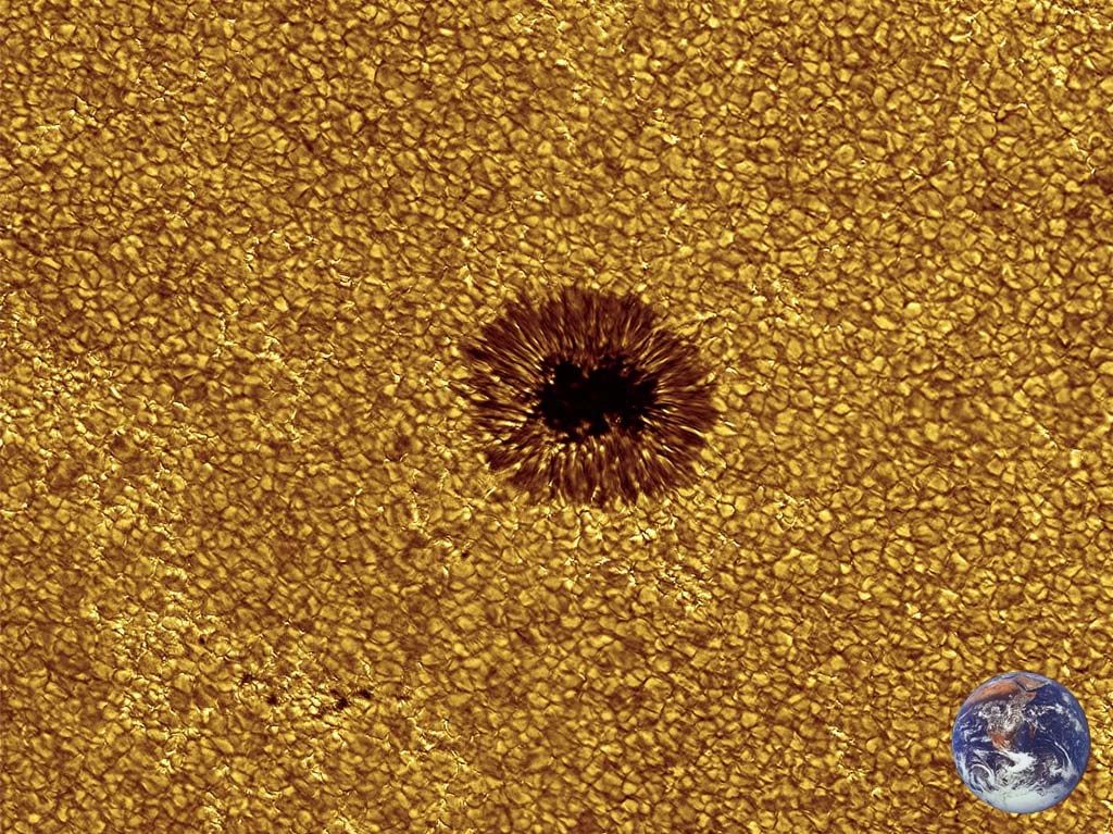 Слънчево петно, с неговата сянка (тъмната част в средата) и полусянка. Петното е на фона на слънчевата повърхност, с ясно изразена зърнеста структура (гранулация).