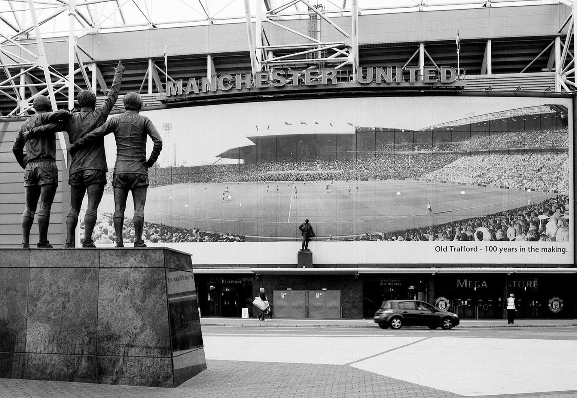 Статуята на Светата троица на Юнайтед - Джордж Бест, Денис Лоу и Боби Чарлтън, бди пред стадиона.