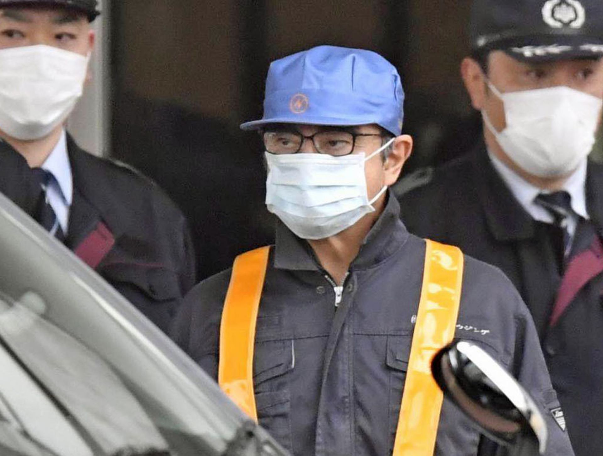 Японски телевизии разпространиха кадри как мъж с маска и синя шапка излиза от стъклените врати на Токийския център за задържане