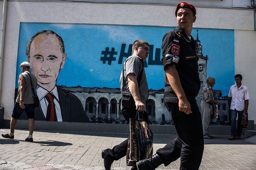 Хората вървят по свежи графити, изобразяващи Владимир Путин в Симферопол на 17 август 2015 г. в Симферопол, Крим