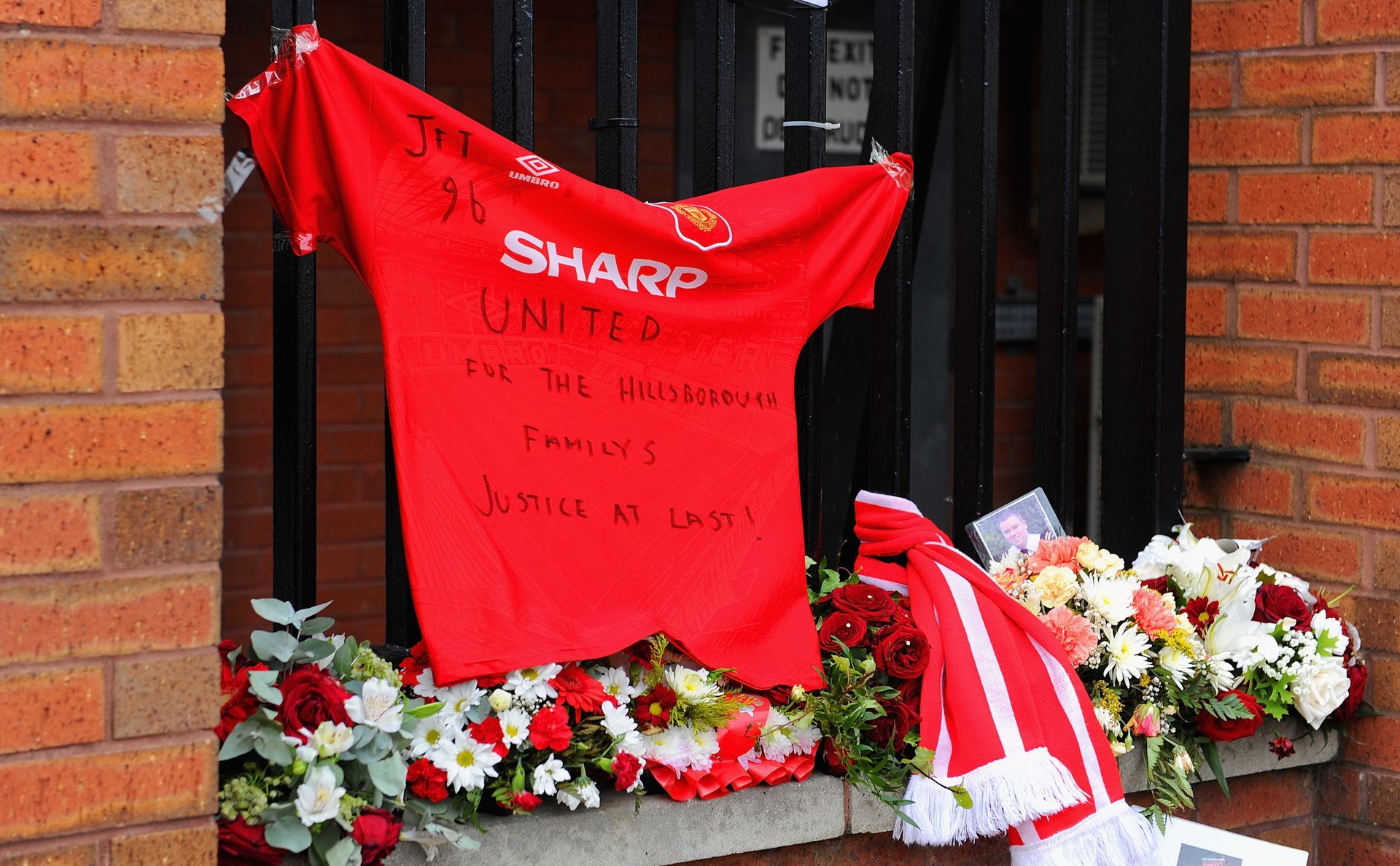 Фланелка на големия футболен враг на Ливърпул - Манчестър Юнайтед, е увиснала до мемориала за жертвите. Солидарност и от този непримирим на терена противник