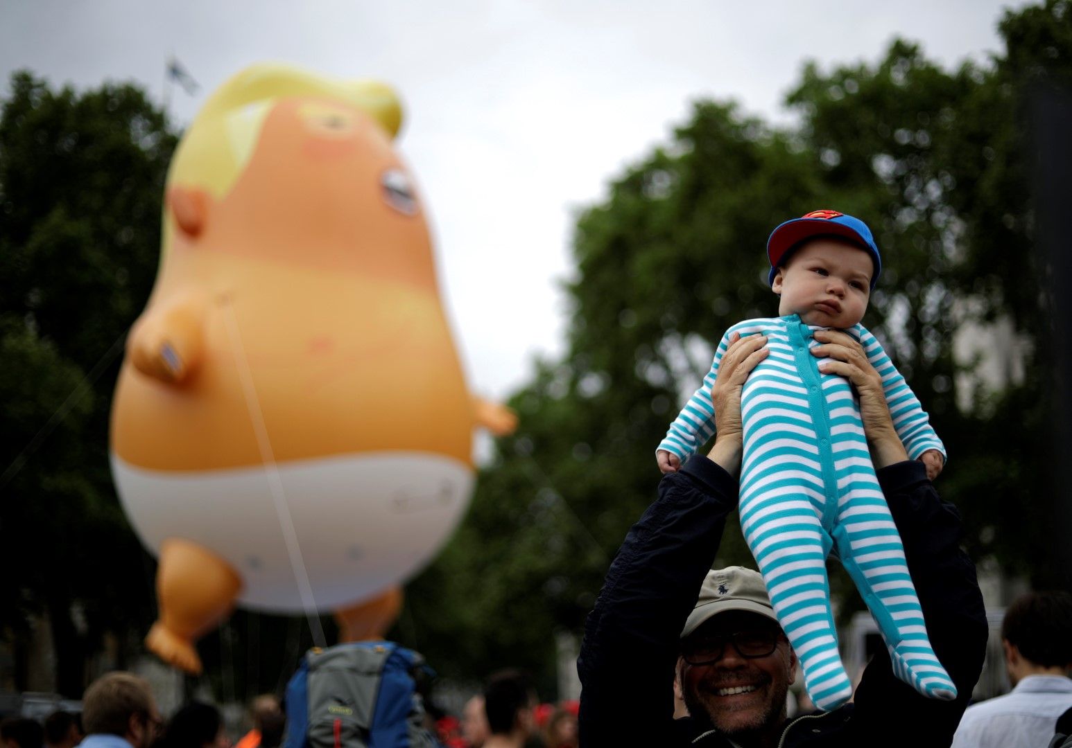 Протестиращ вдига бебето си, редом до "бебето" Тръмп