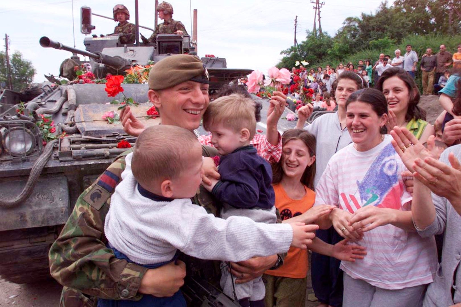 13 юни 1999 г. британски войник от силите на НАТО държи две деца етнически албанци в Прищина