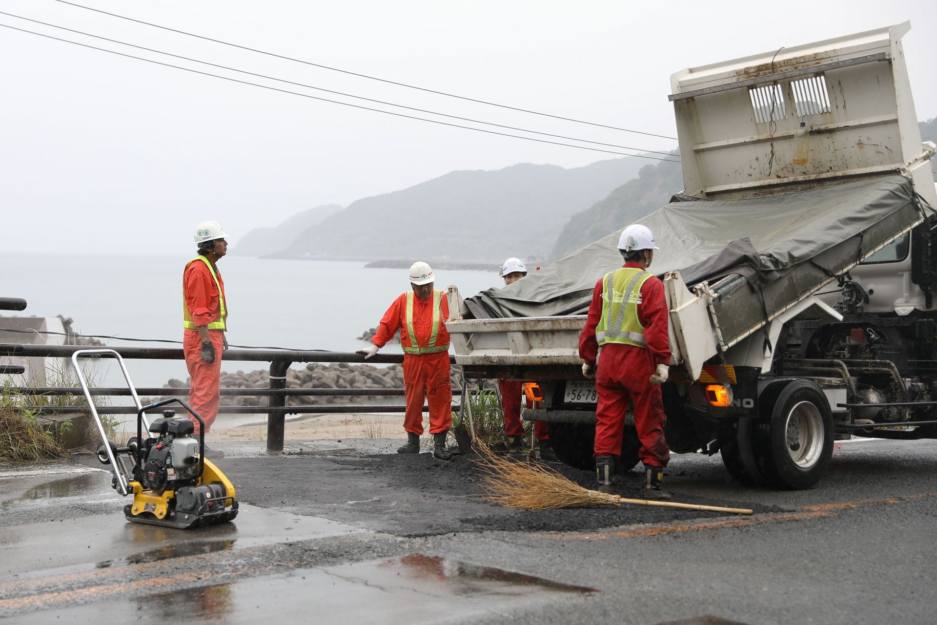 Работници асфалтират път, разрушен при труса
