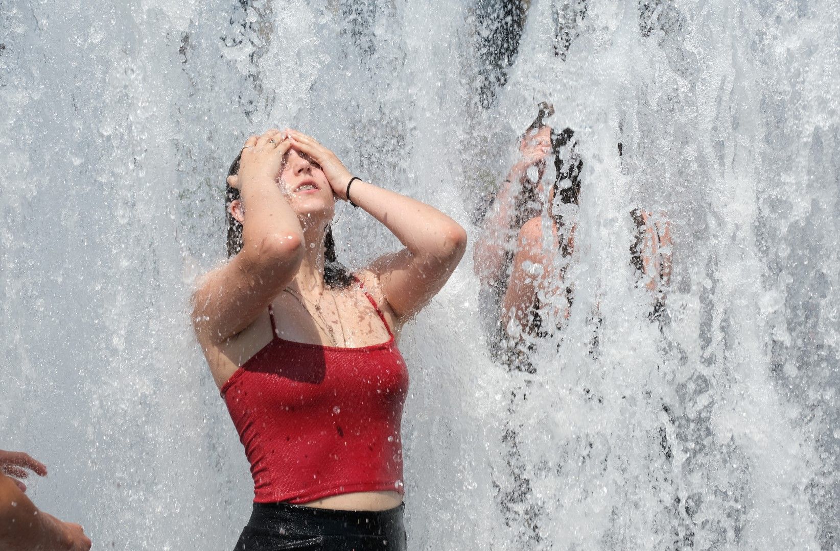 Момиче се разхлажда от жегата на фонтан в Берлин, 26 юни 2019 г.
