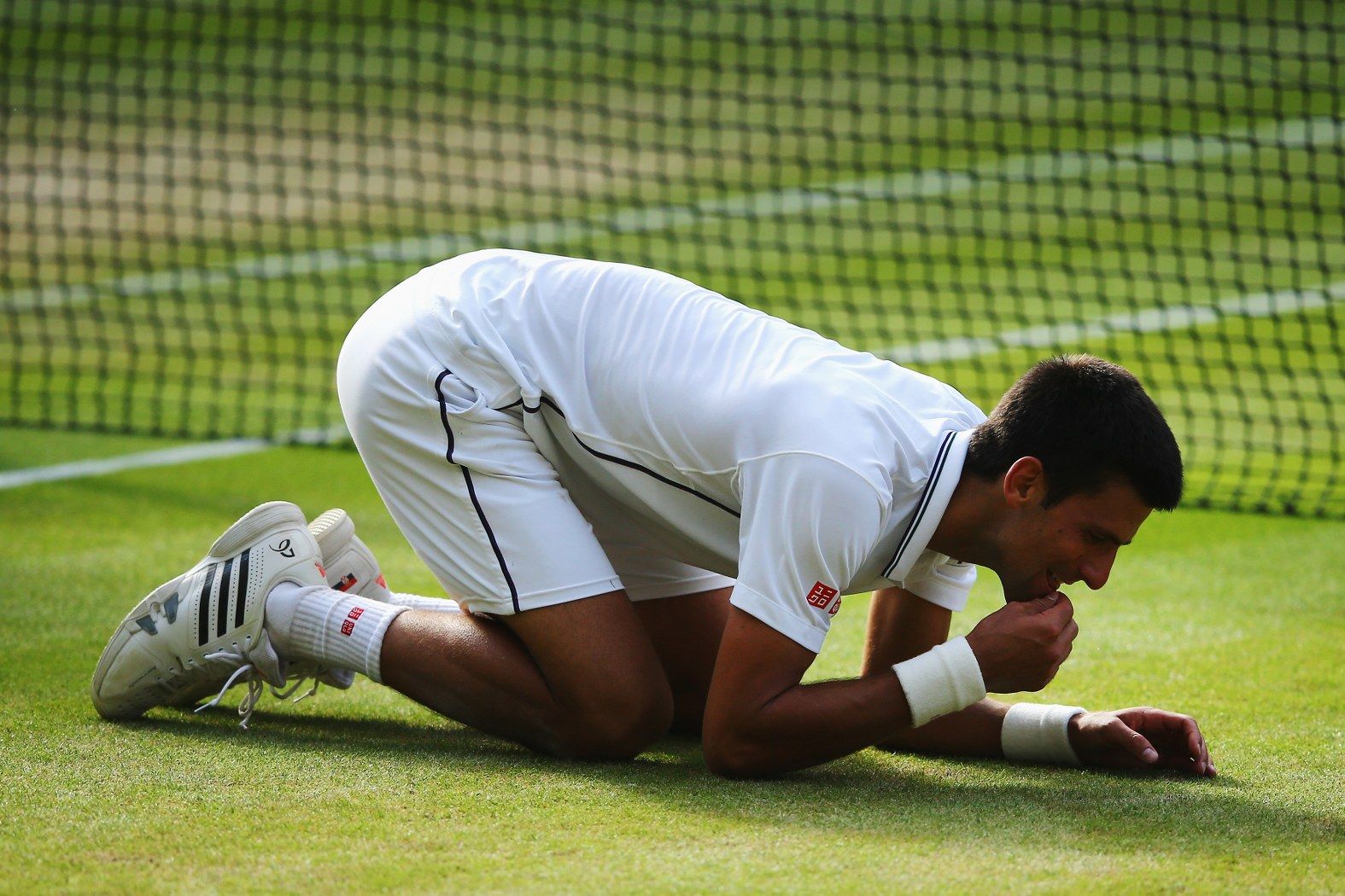 Новак Джокович дъвче тревата на "Уимбълдън", след като спечели турнира през юни в драматичен финал срещу Роджър Федерер