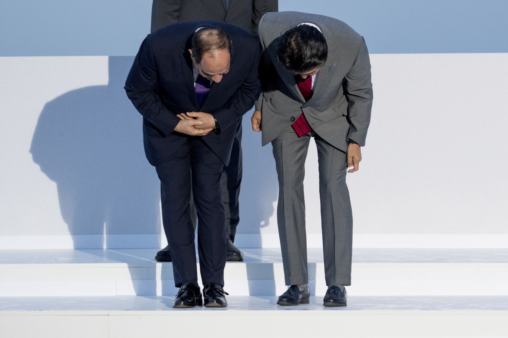 Египетският президент Абдел Фатах ел-Сиси, вляво и японският премиер Шинцо Абе, вдясно, търсят имената им, докато пристигат за снимката на групата G7