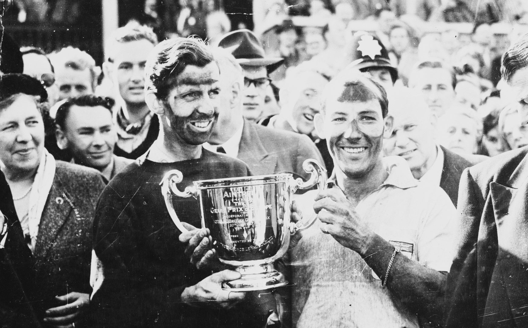 1957-а Стърлинг Мос и съотборникът му Тони Брукс държат трофея след победата си на Гран при на Великобритания в Ливърпул.