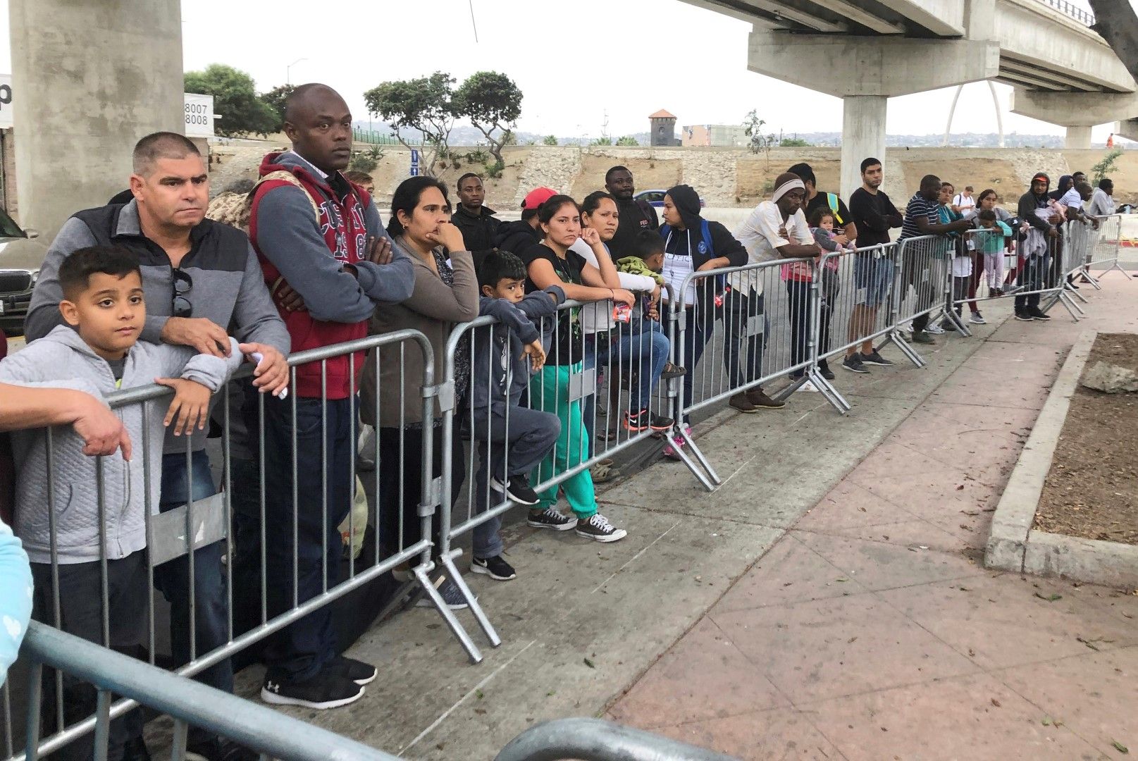 Мигранти, търсещи убежище, слушат имена, извиквани от списъка на чакащите, за да поискат убежище на граничен пункт в Сан Диего, 26 септември 2019 г. 