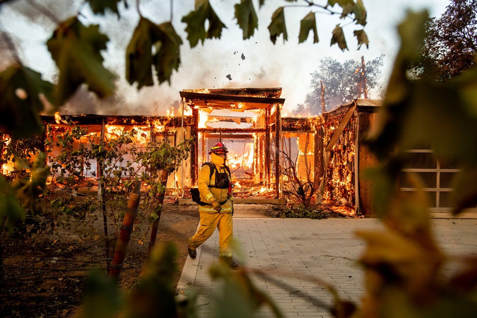 Пожарникар минава покрай изгоряла къща
