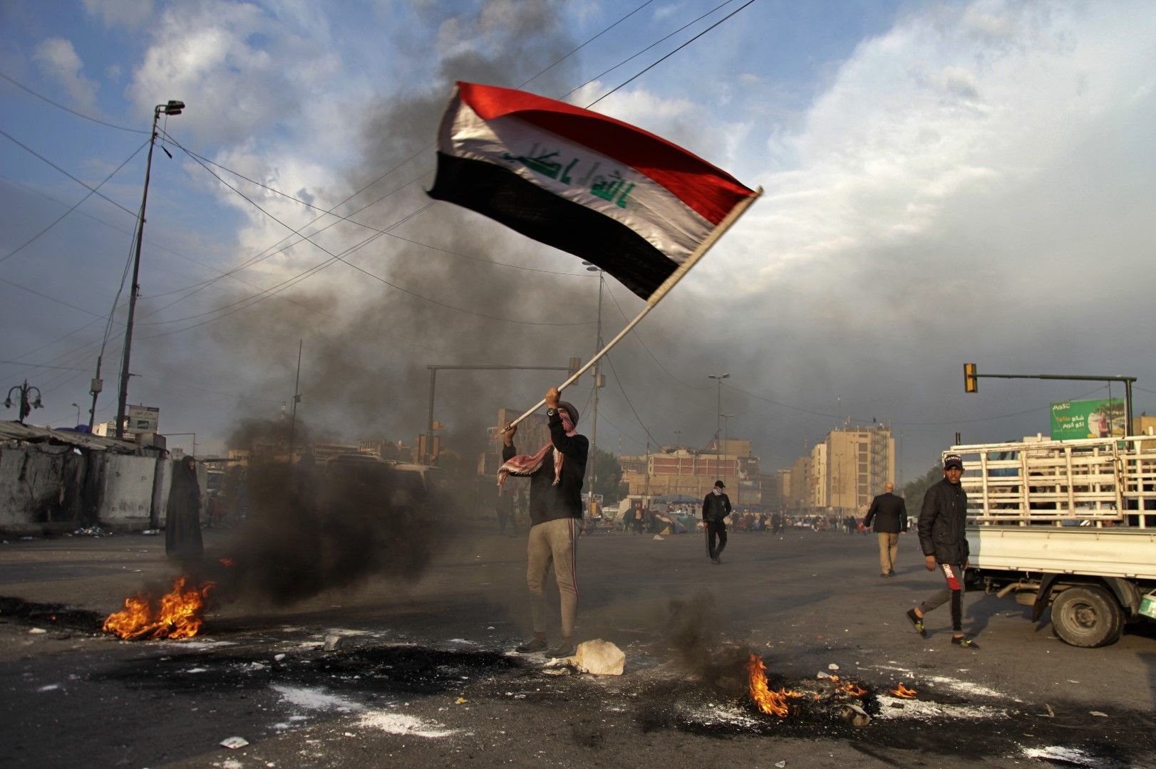 Протестиращ развява иракското знаме на опразнения площад Тахир в Багдад, като демонстрира против иранските удари по военни бази в страната му