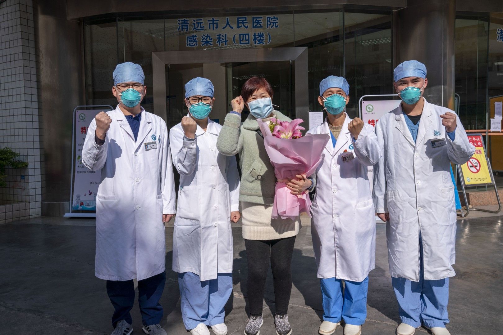 Излекуван пациент от заболяване, причинено от новия коронавирус, позира с медици пред болница в китайски град, 30 януари