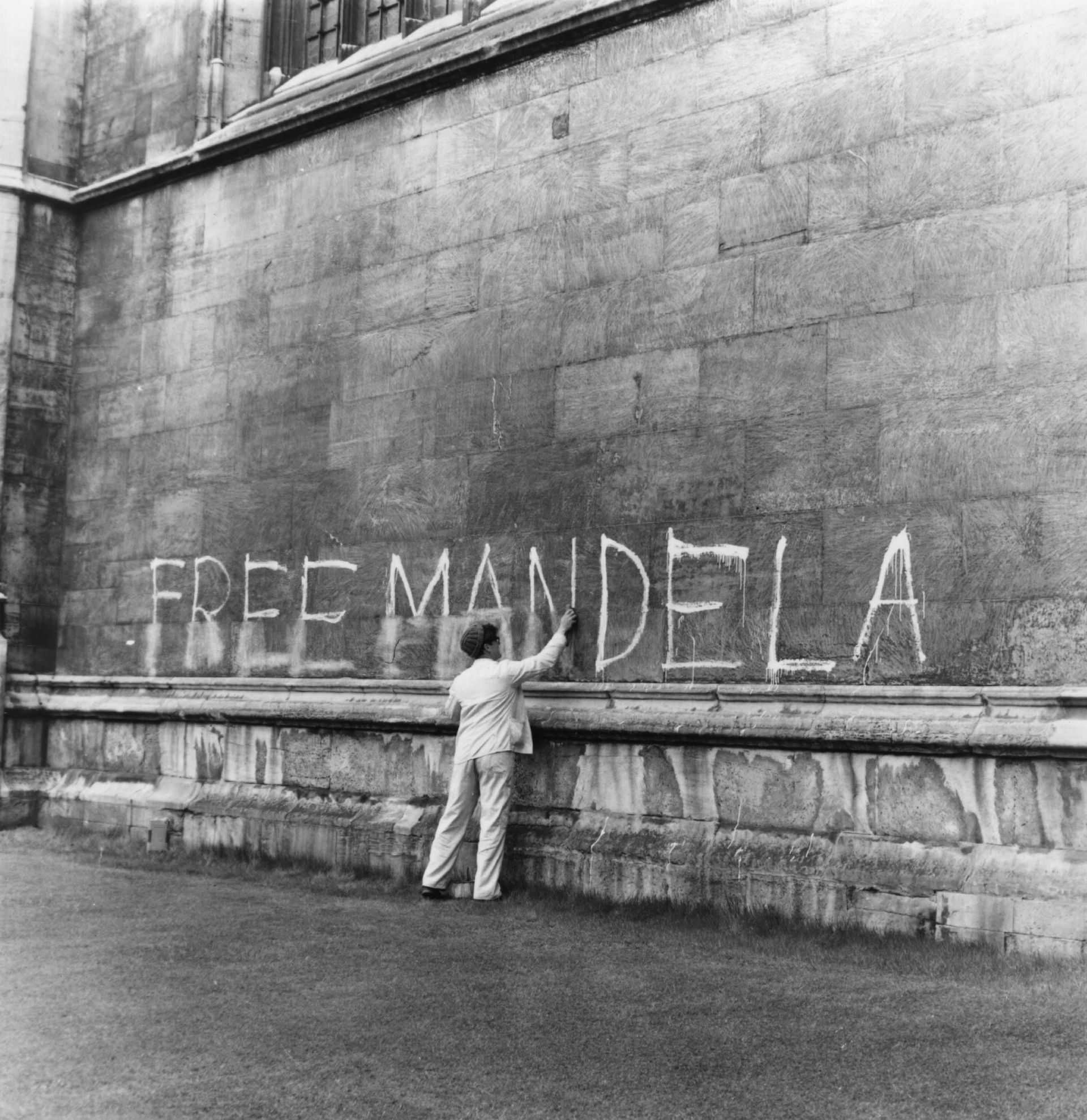 Мъж трие надписа "Свобода за Мандела" в Кингс колидж в Кеймбридж