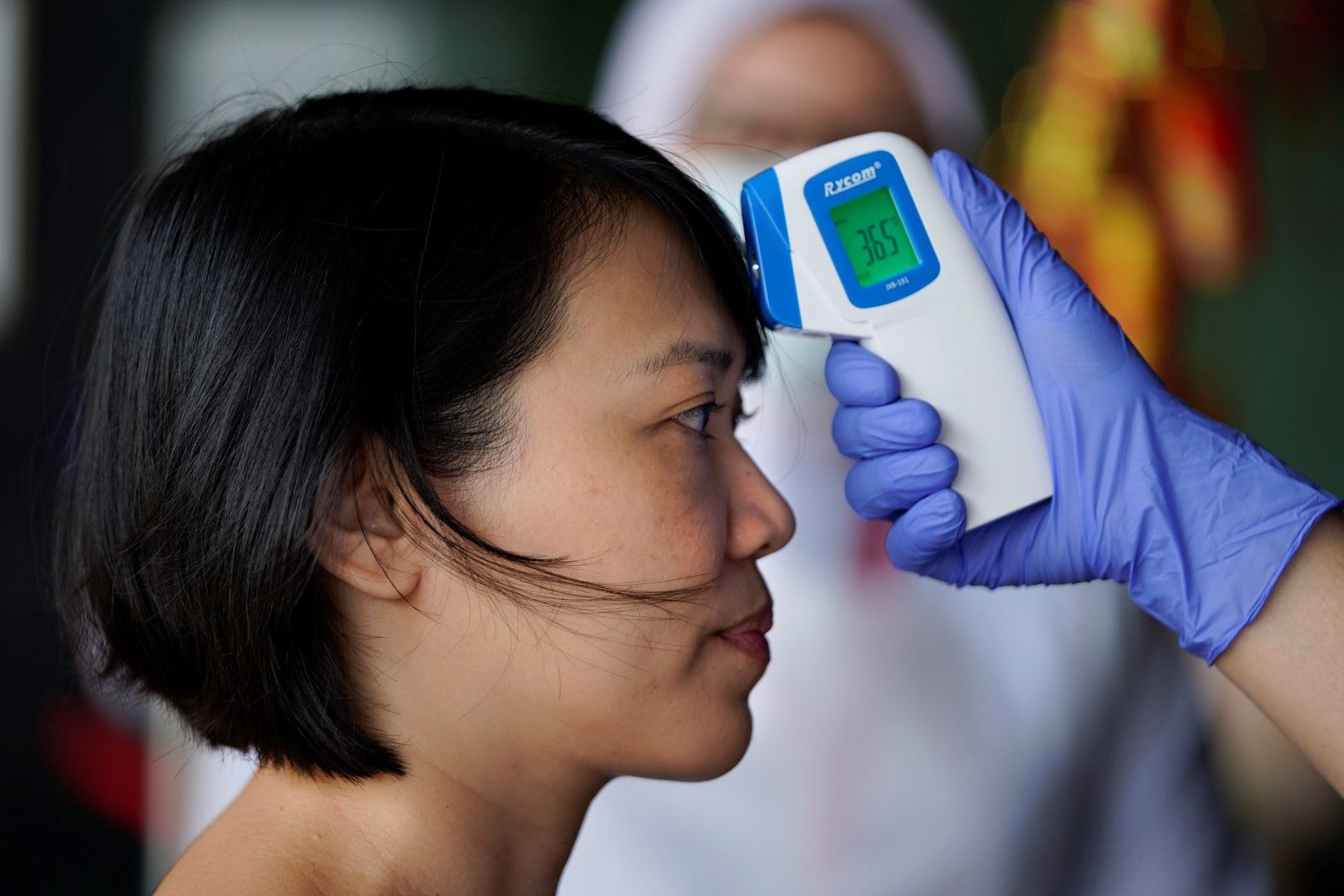 Медицинска сестра проверява температурата на посетителка в болница в Куала Лампур, Малайзия