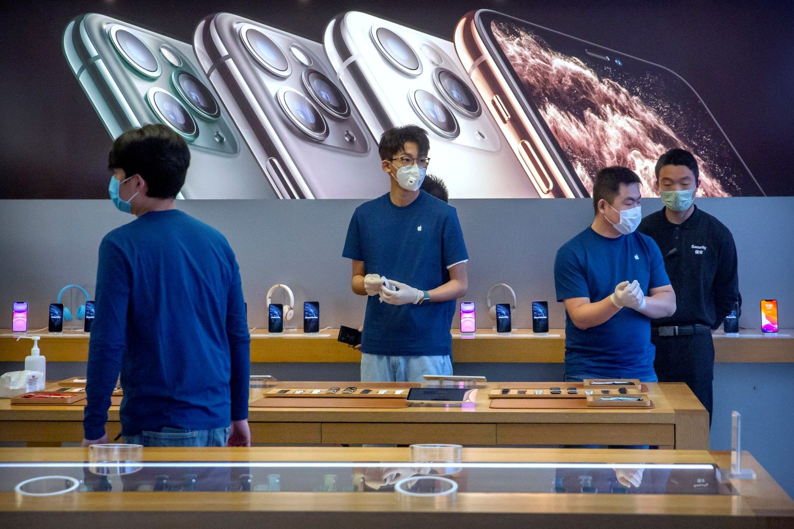 Служители с маски обслужват току-що отворен отново магазин на Епъл (Apple) в Пекин