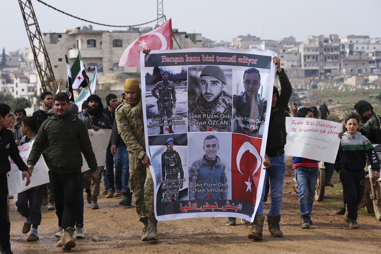 14 февруари - Сирийци държат плакати със снимки на убити бунтовници и турски войници край град Биниш, провинция Идлиб