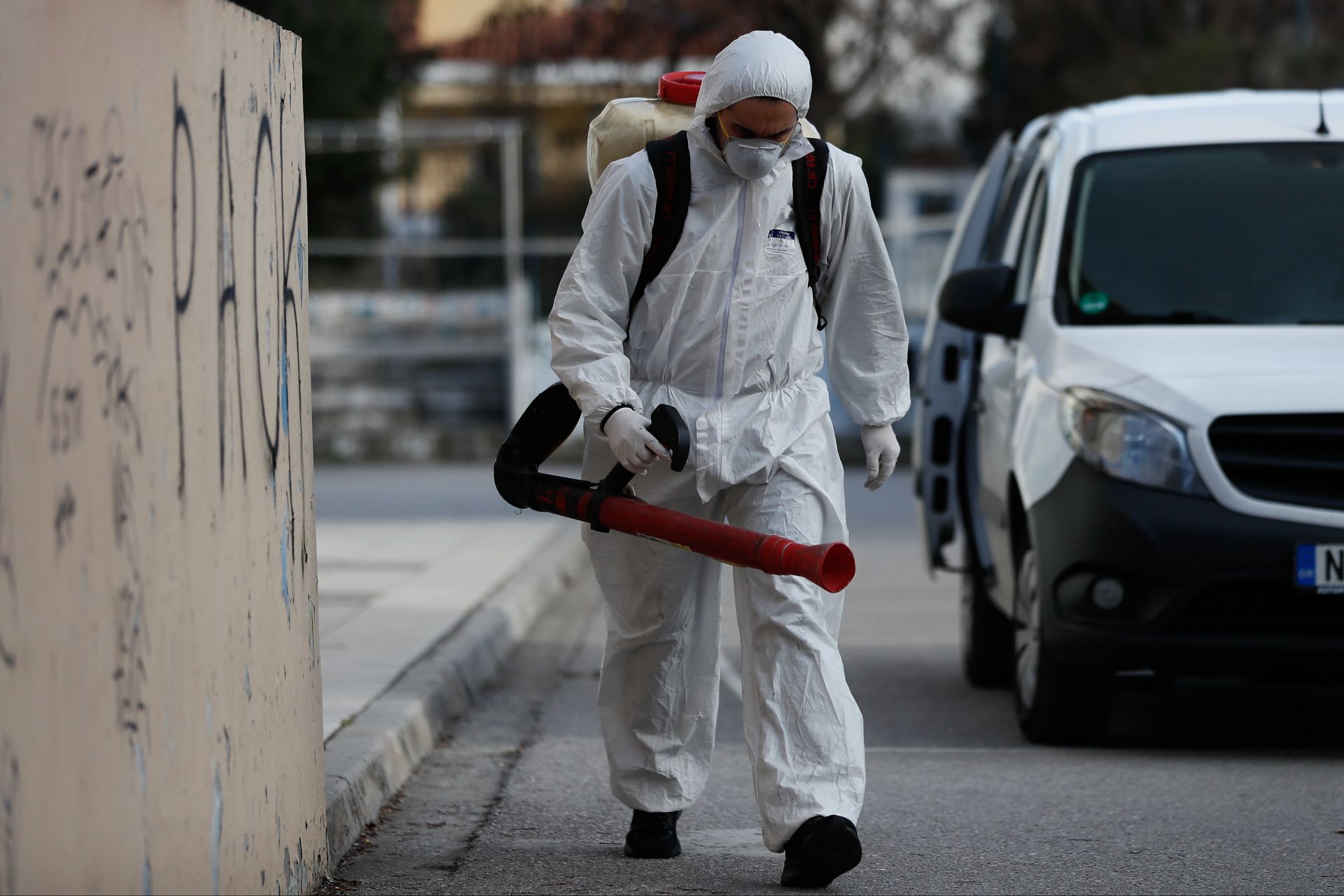 Мъж, облечен със защитен костюм, обеззаразява основното училище, където на детето е поставена диагноза коронавирус в Солун